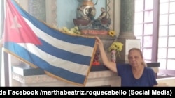 ARCHIVO. La opositora cubana posa con una bandera cubana ante una imagen de la Virgen de la Caridad del Cobre, la Patrona de Cuba.